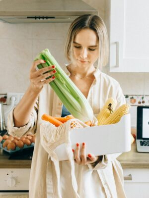 Woman in White Robe Holding Green Plastic Pack